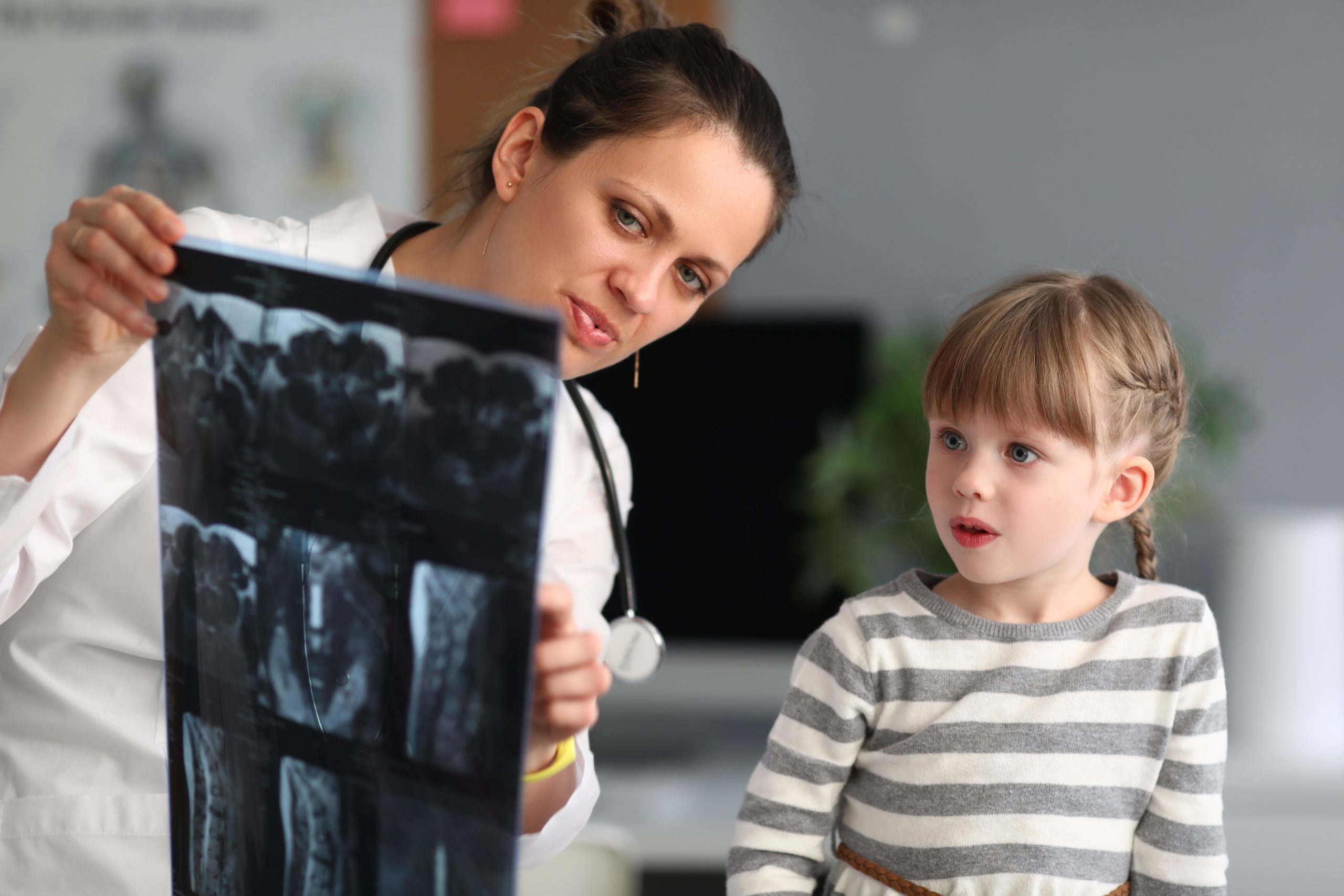 Woman doctor shows child patient an xray in clinic